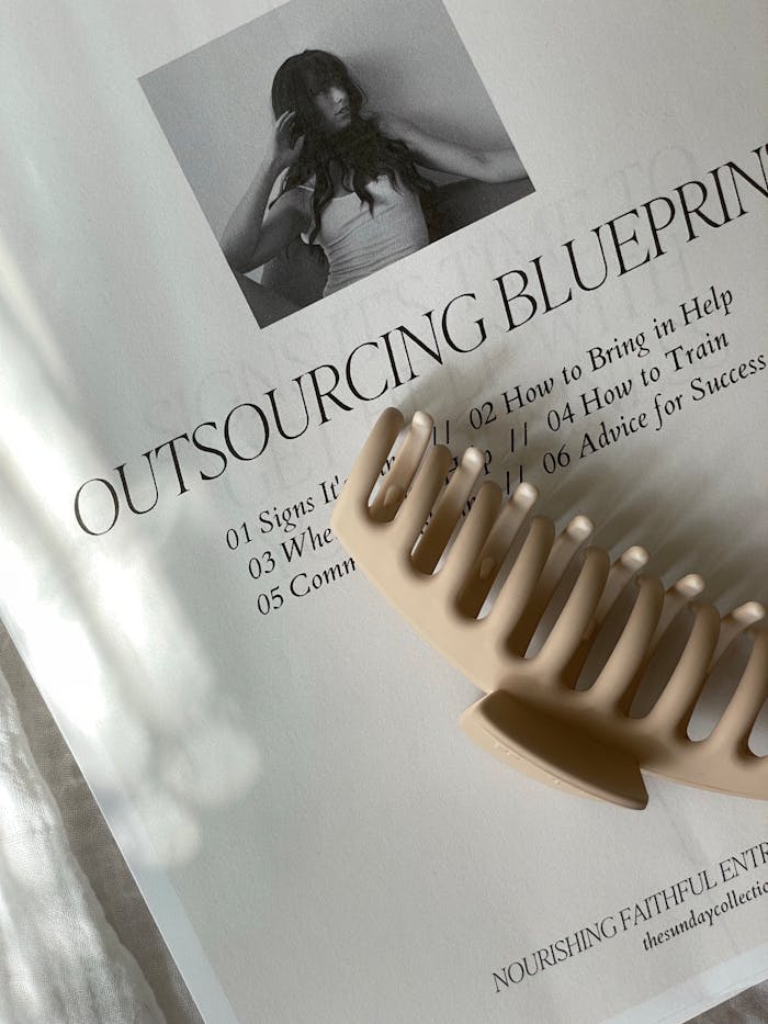 Close-up of a hair clip on a book page with text and image in soft lighting.
